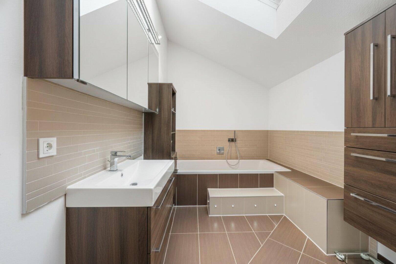 Modernes Badezimmer mit Badewanne, Dachfenster und eleganten Holzschränken.
