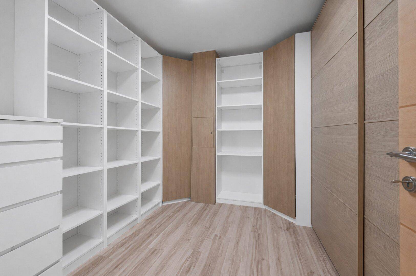 Geräumiger begehbarer Kleiderschrank mit vielen Regalen und Stauraum.