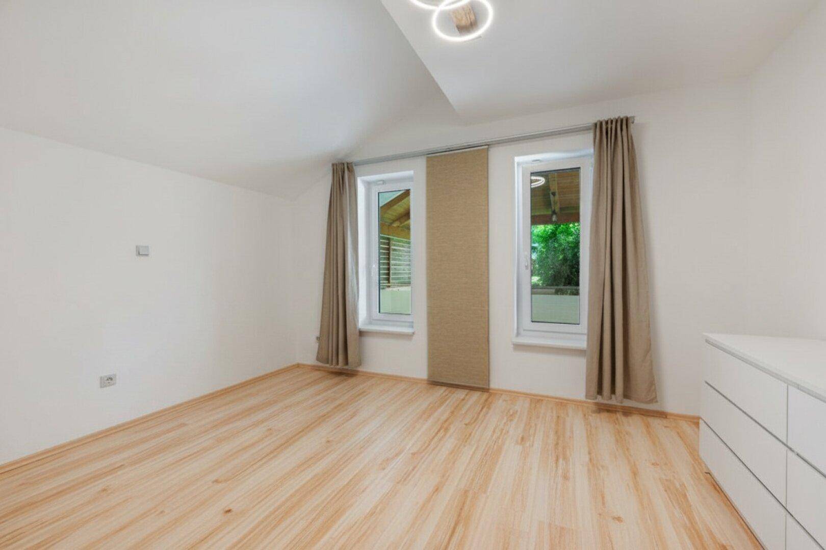 Helles Schlafzimmer mit Holzboden und Dachschräge, bereit zur individuellen Gestaltung.
