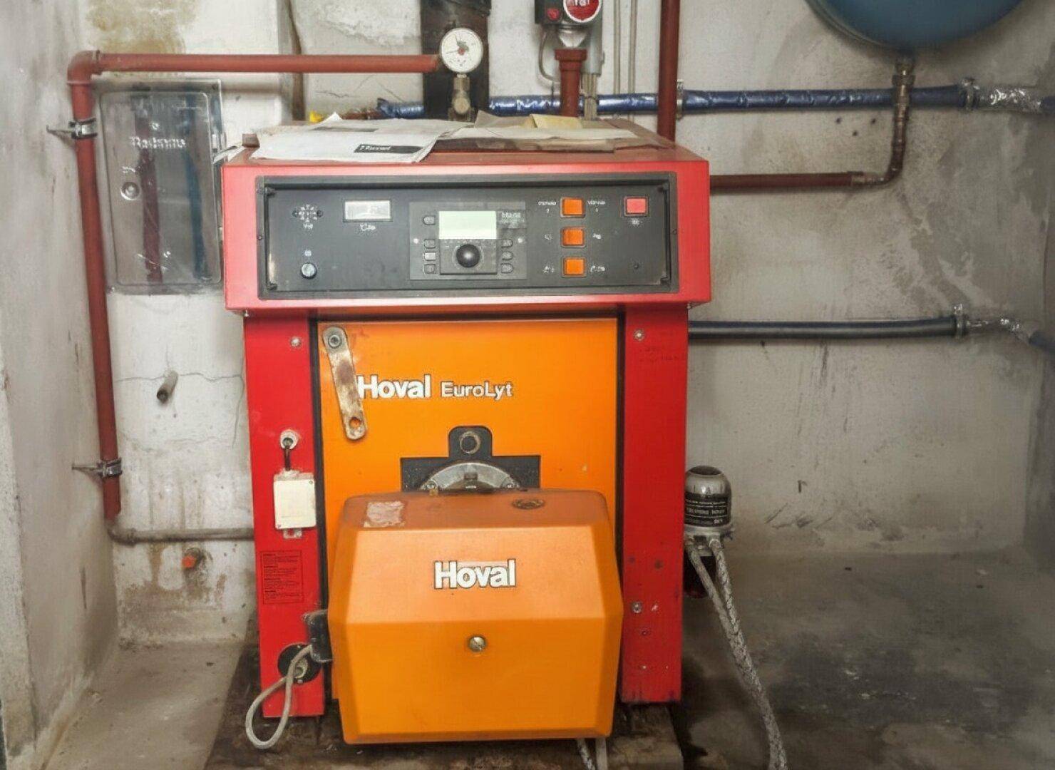 Heizungsanlage Hoval EuroLyt in einem Technikraum mit sichtbaren Rohren und Messgeräten.