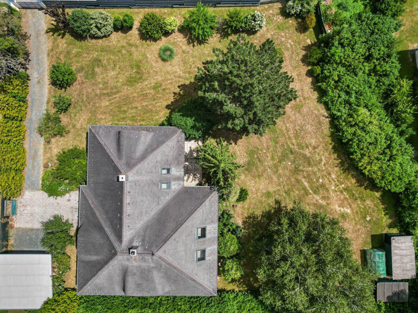 Luftaufnahme eines Hauses mit großem Garten und altem Baumbestand in ländlicher Umgebung.