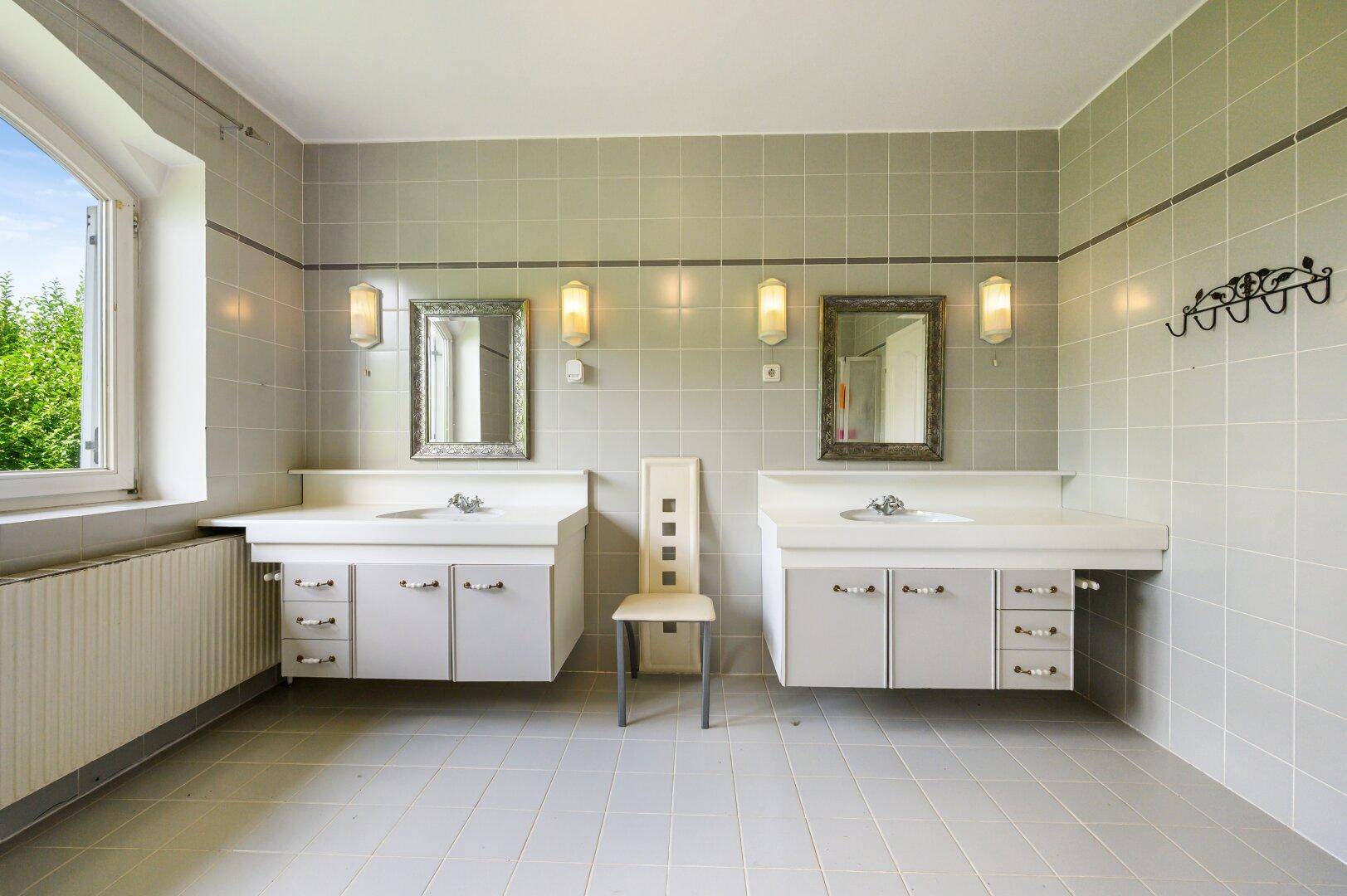Großes Badezimmer mit zwei Waschbecken, Spiegeln und hellen Fliesen.