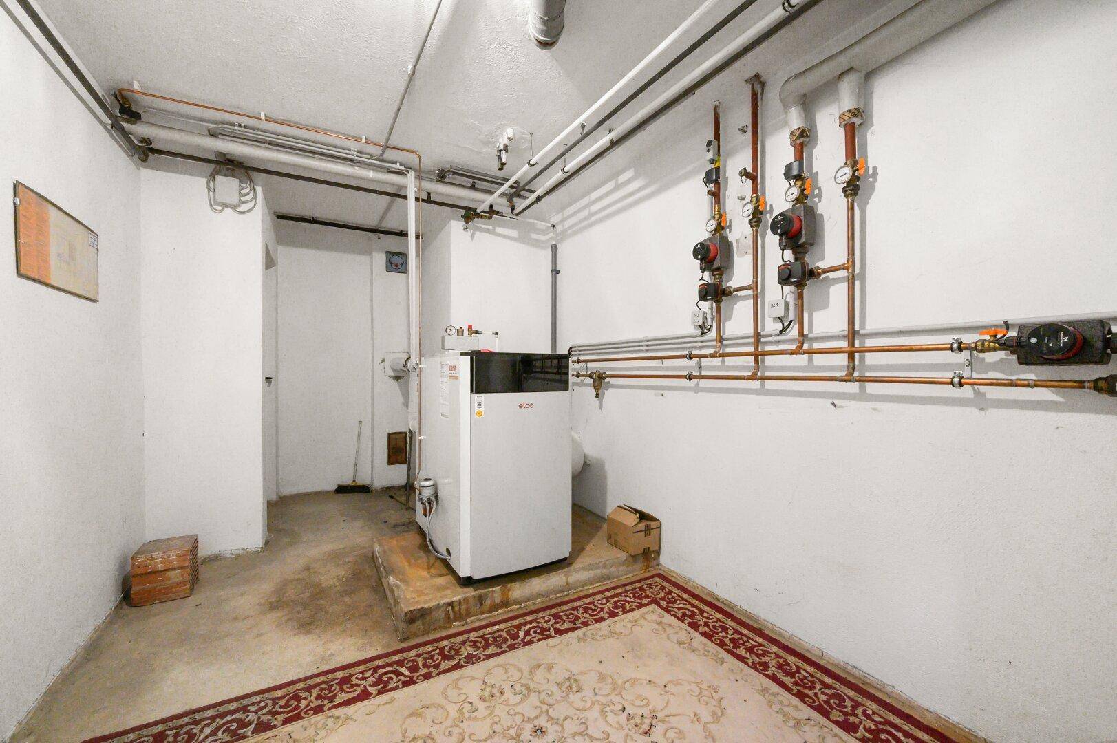 Heizraum im Keller mit moderner Heizungsanlage und sichtbaren Rohrleitungen.