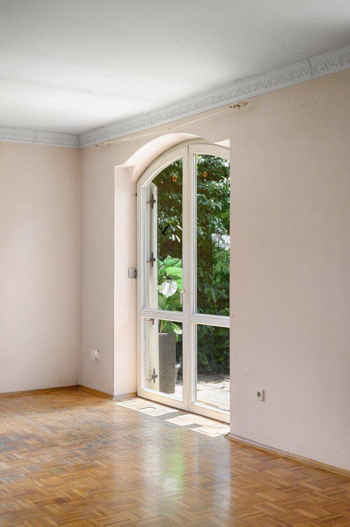 Detailansicht einer hohen Fenstertür im Wohnzimmer mit Blick auf die grüne Umgebung.