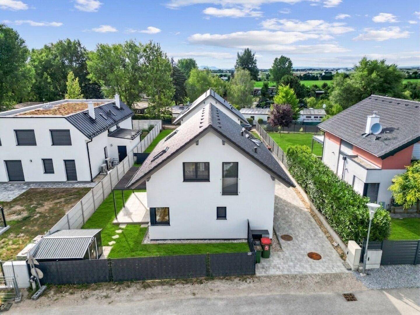 Draufsicht auf das moderne Einfamilienhaus mit Zufahrt und gepflegtem Gartenbereich.