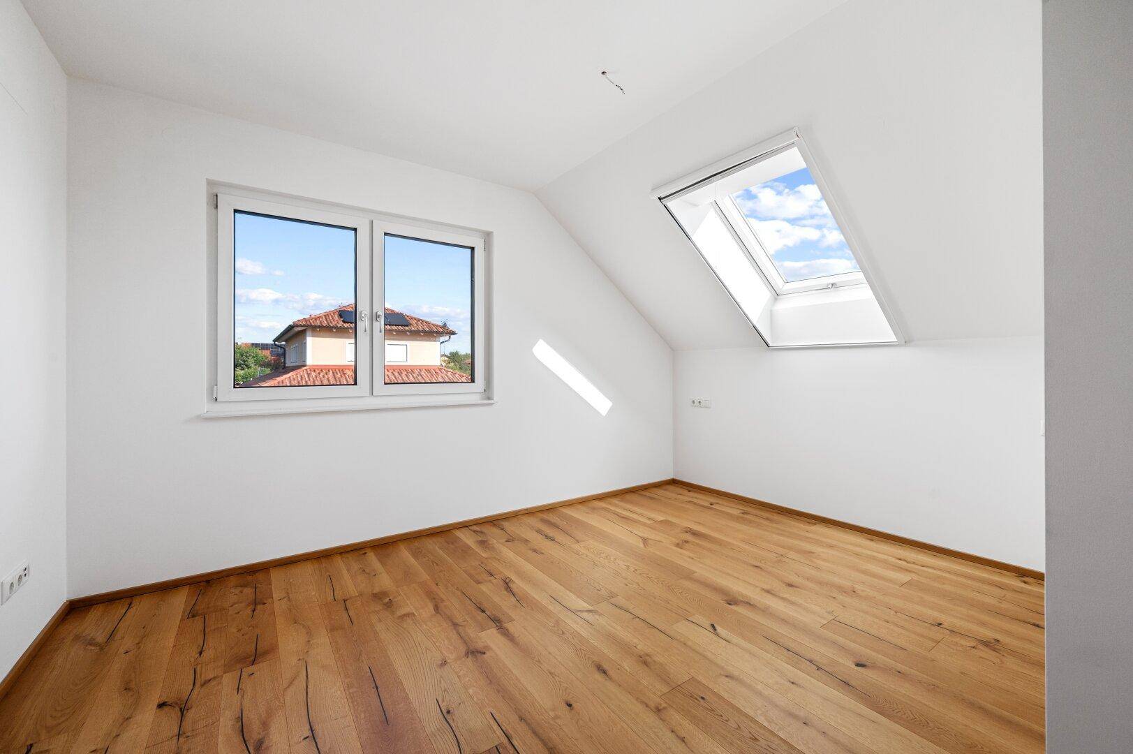 Geräumiges Zimmer mit Eichenparkett, Fenster und zusätzlichem Dachfenster für viel Licht.