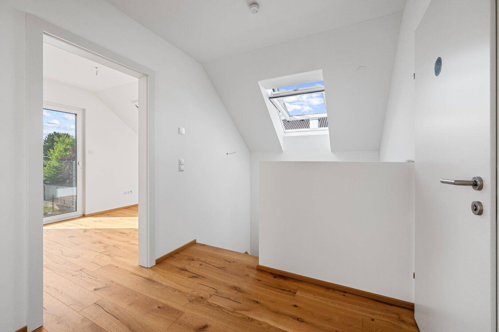 Heller Flur im Obergeschoss mit Eichenparkett, Dachfenster und Zugang zu weiteren Räumen.