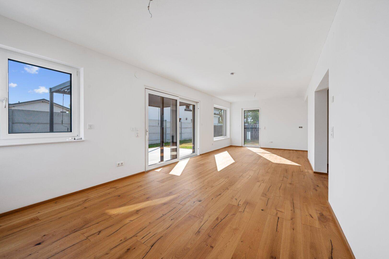 Helles Wohnzimmer mit Eichenparkett, großen Fenstern und direktem Zugang zum Garten.