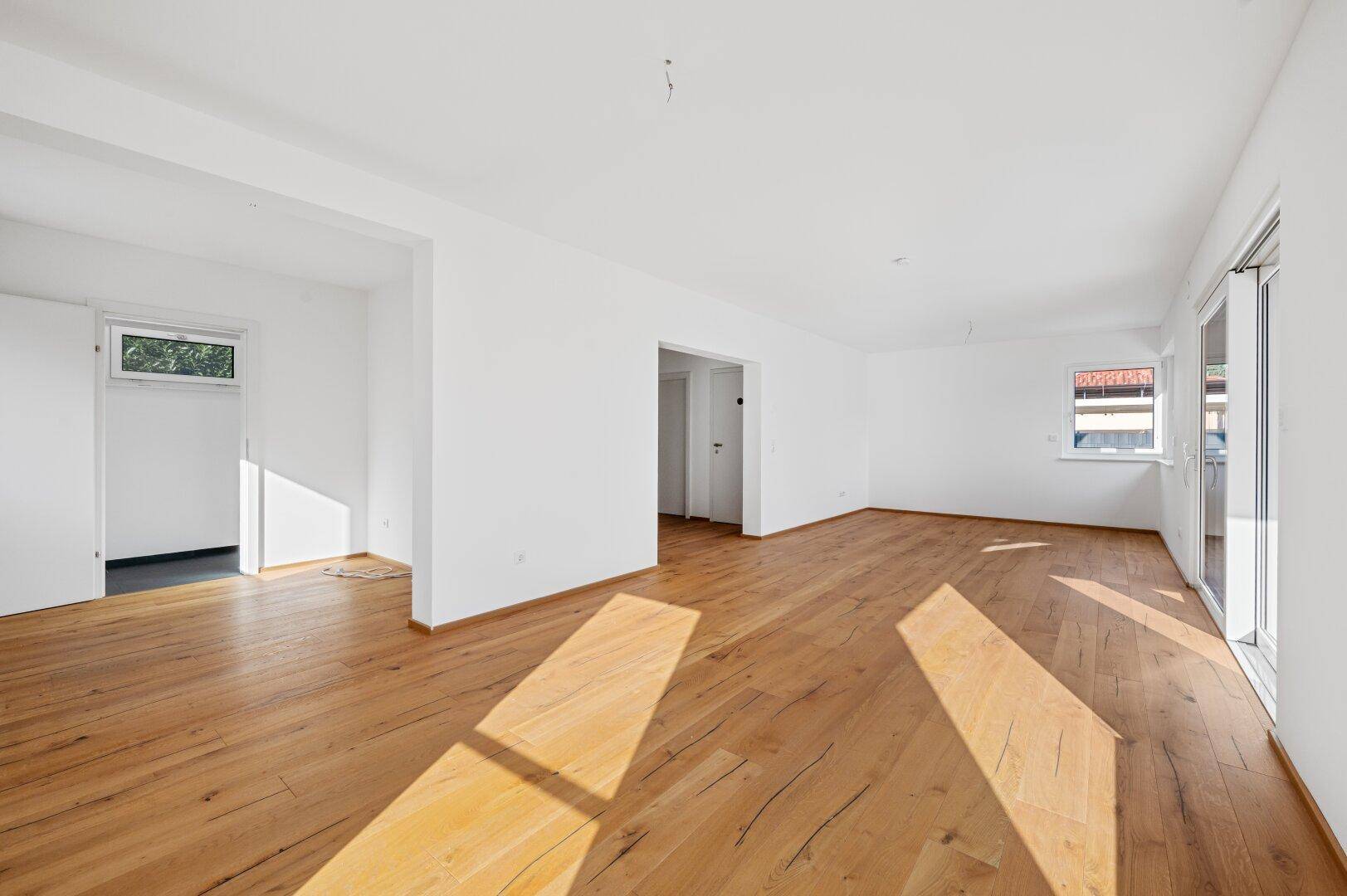 Geräumiges, leeres Wohnzimmer mit Eichenparkett und offener Verbindung zu angrenzenden Räumen.