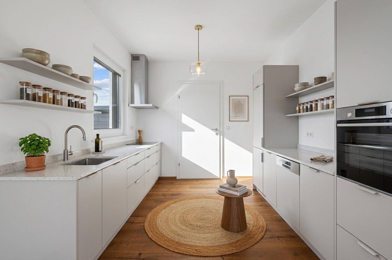 Moderne Küche mit hellgrauen Schränken, Holzboden, Fenster und integrierten Geräten.