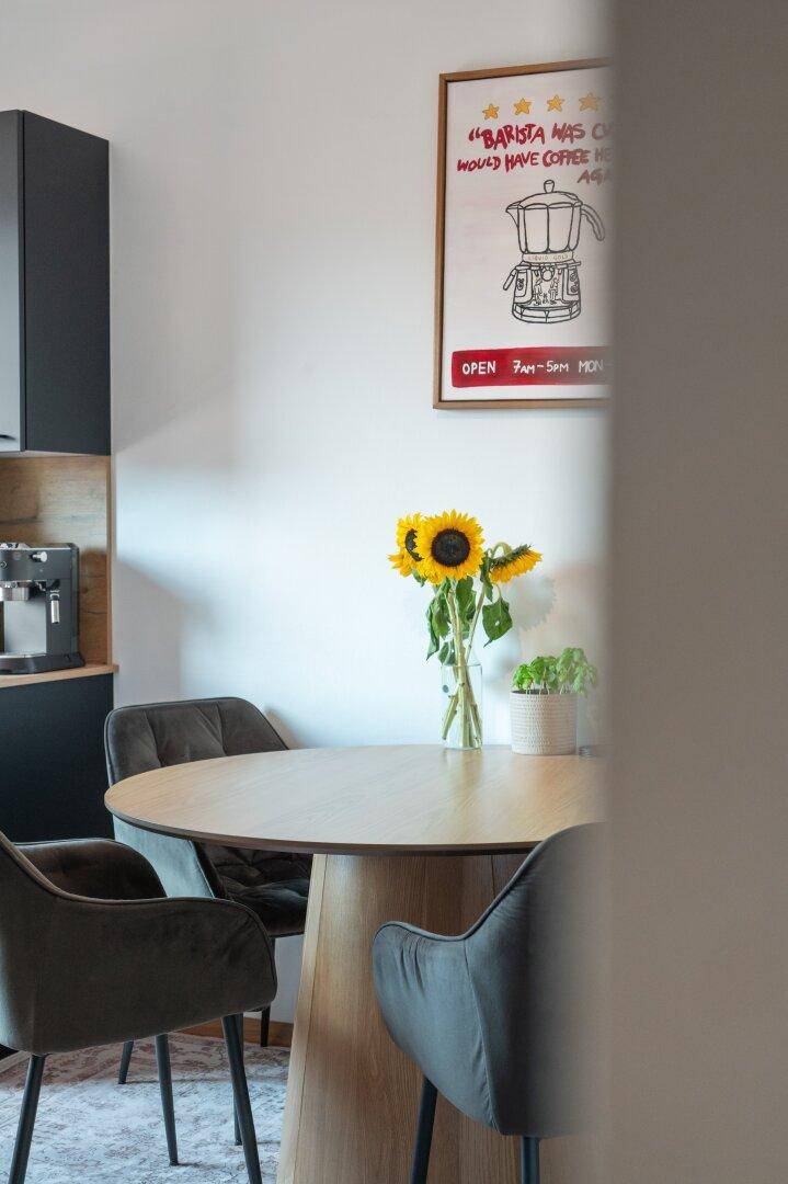 Detailaufnahme des Esstisches in der Küche mit Sonnenblumen und dekorativen Bildern.