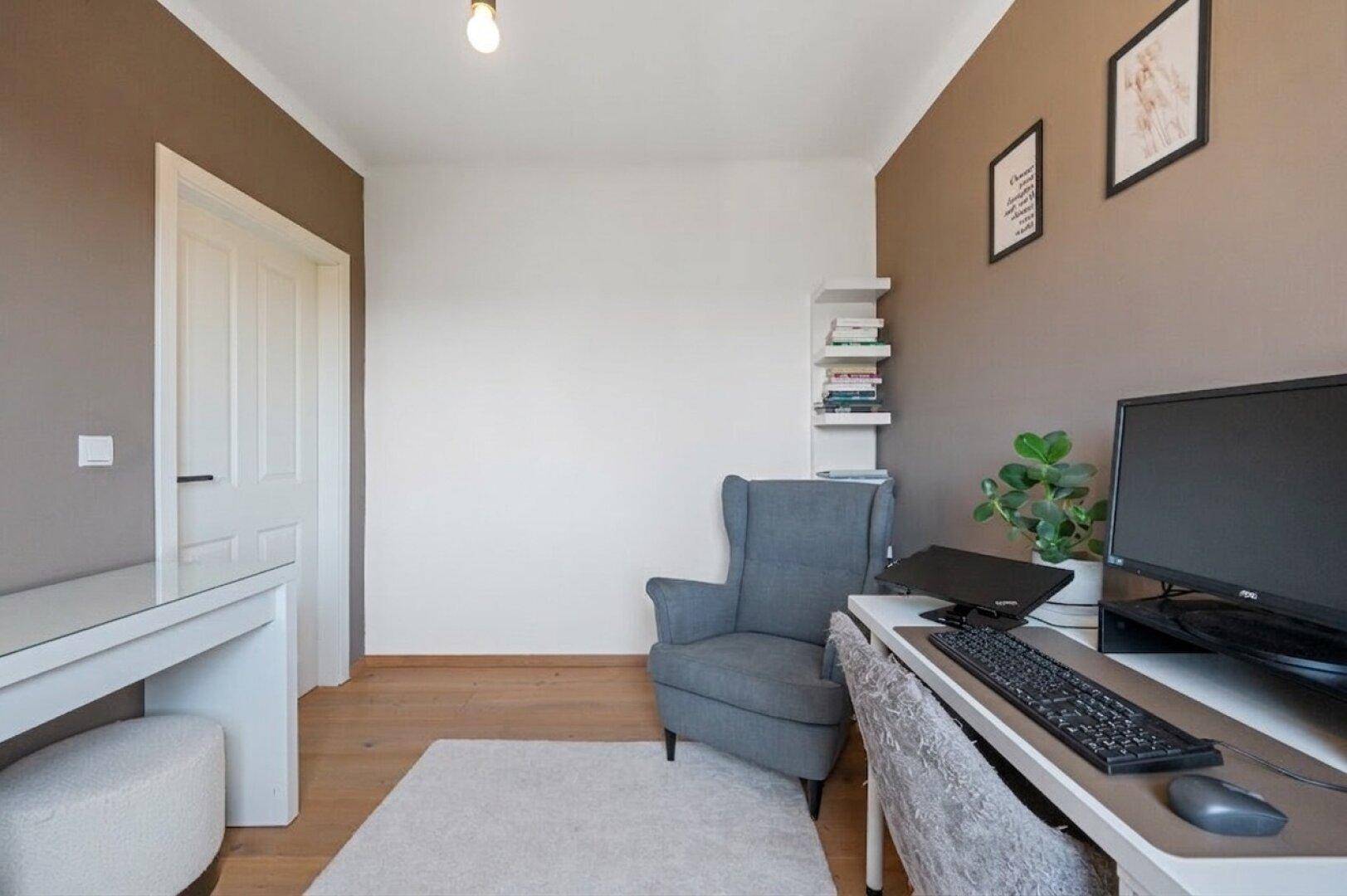Gemütliches Arbeitszimmer mit Sessel, Schreibtisch und Holzboden, ideal für konzentriertes Arbeiten.