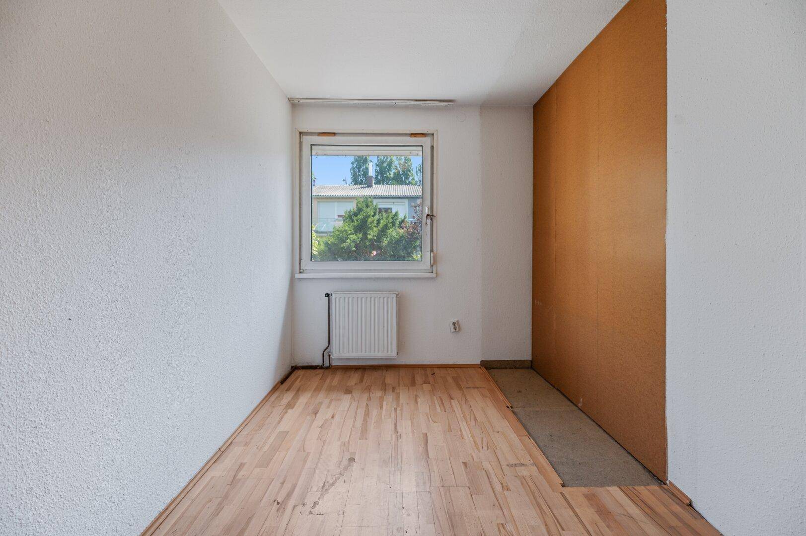 Helles Zimmer mit Holzboden und Fenster, ideal als Büro oder Schlafzimmer nutzbar.