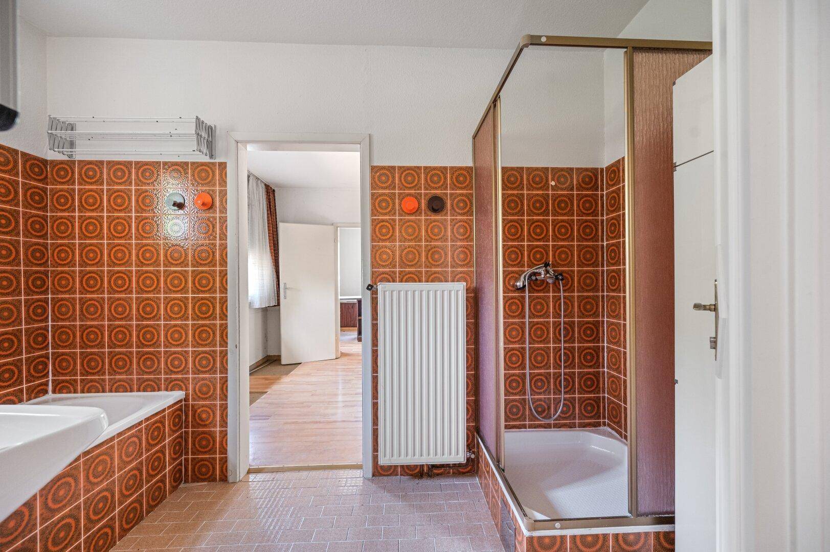 Badezimmer im Stil der 80er Jahre mit orangefarbenen Fliesen und Duschkabine.