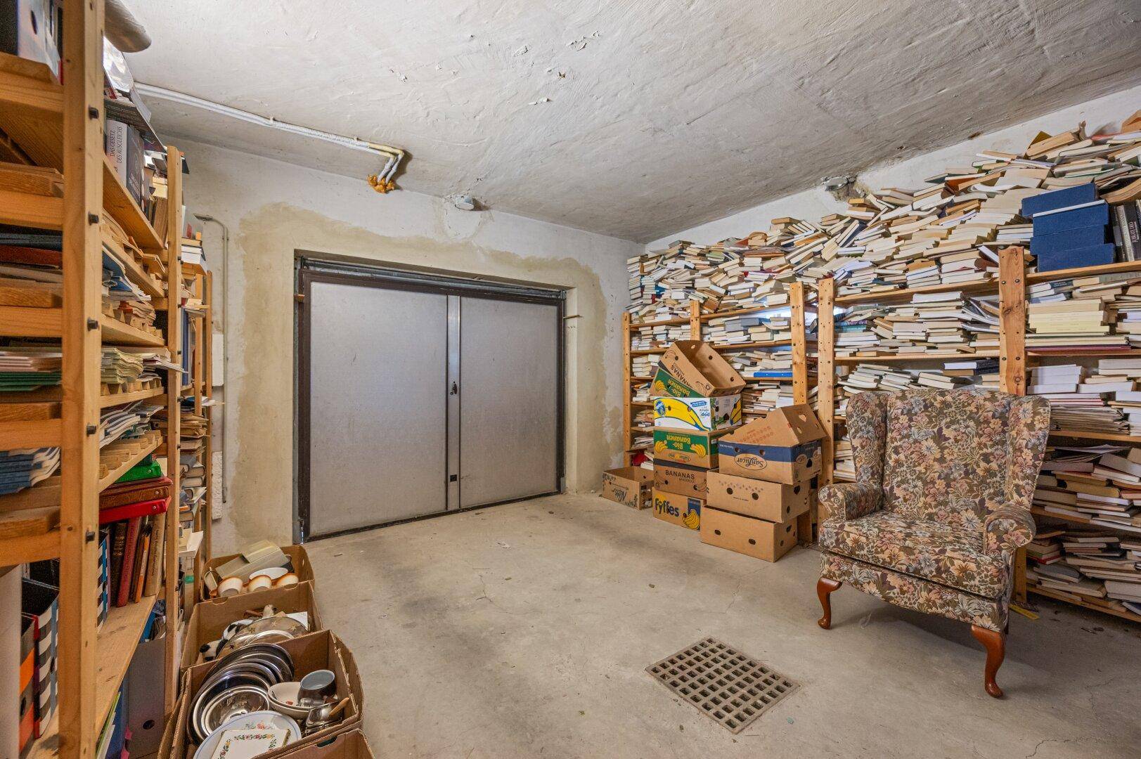 Geräumiger Abstellraum oder Keller mit vielen Büchern, Regalen und einem Sessel.