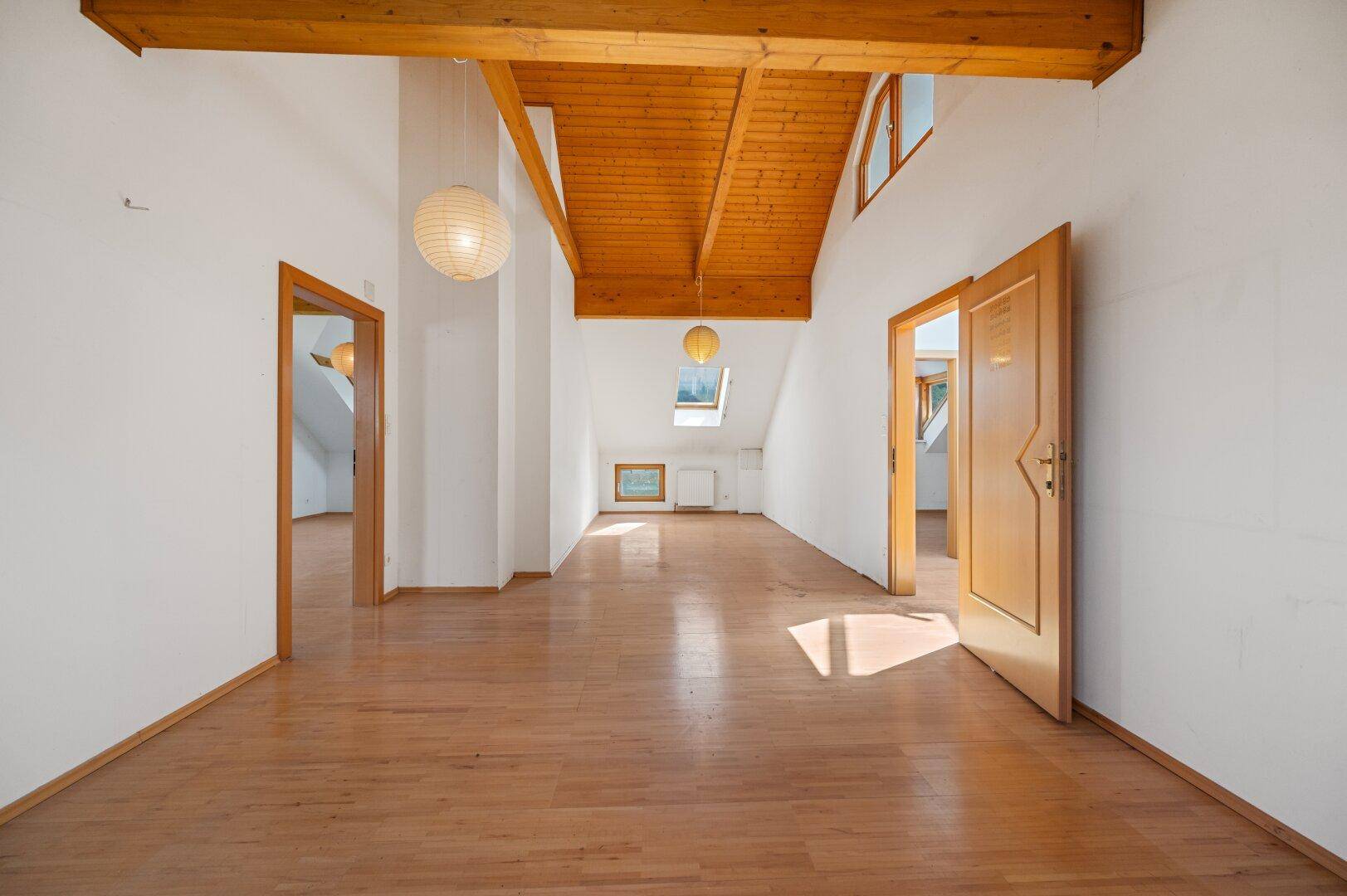Geräumiger Flur im Dachgeschoss mit Holzbalkendecke, Dachschräge und viel Tageslicht.
