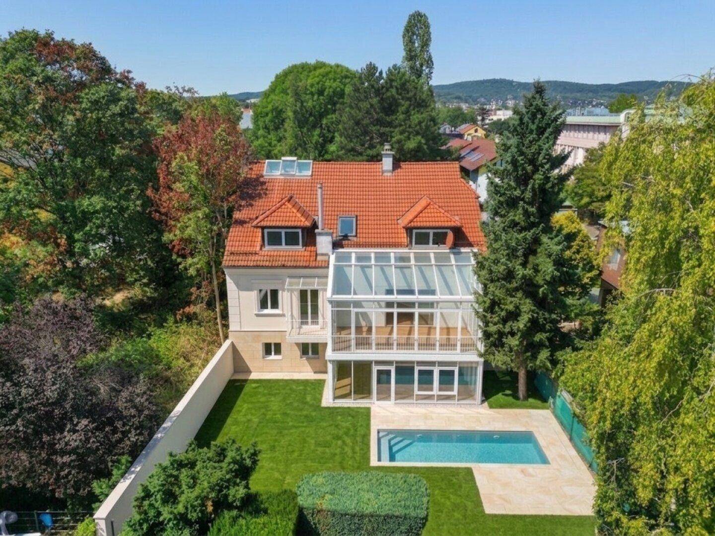 Luftaufnahme des Hauses mit großem Garten, Swimmingpool und verglastem Wintergarten.