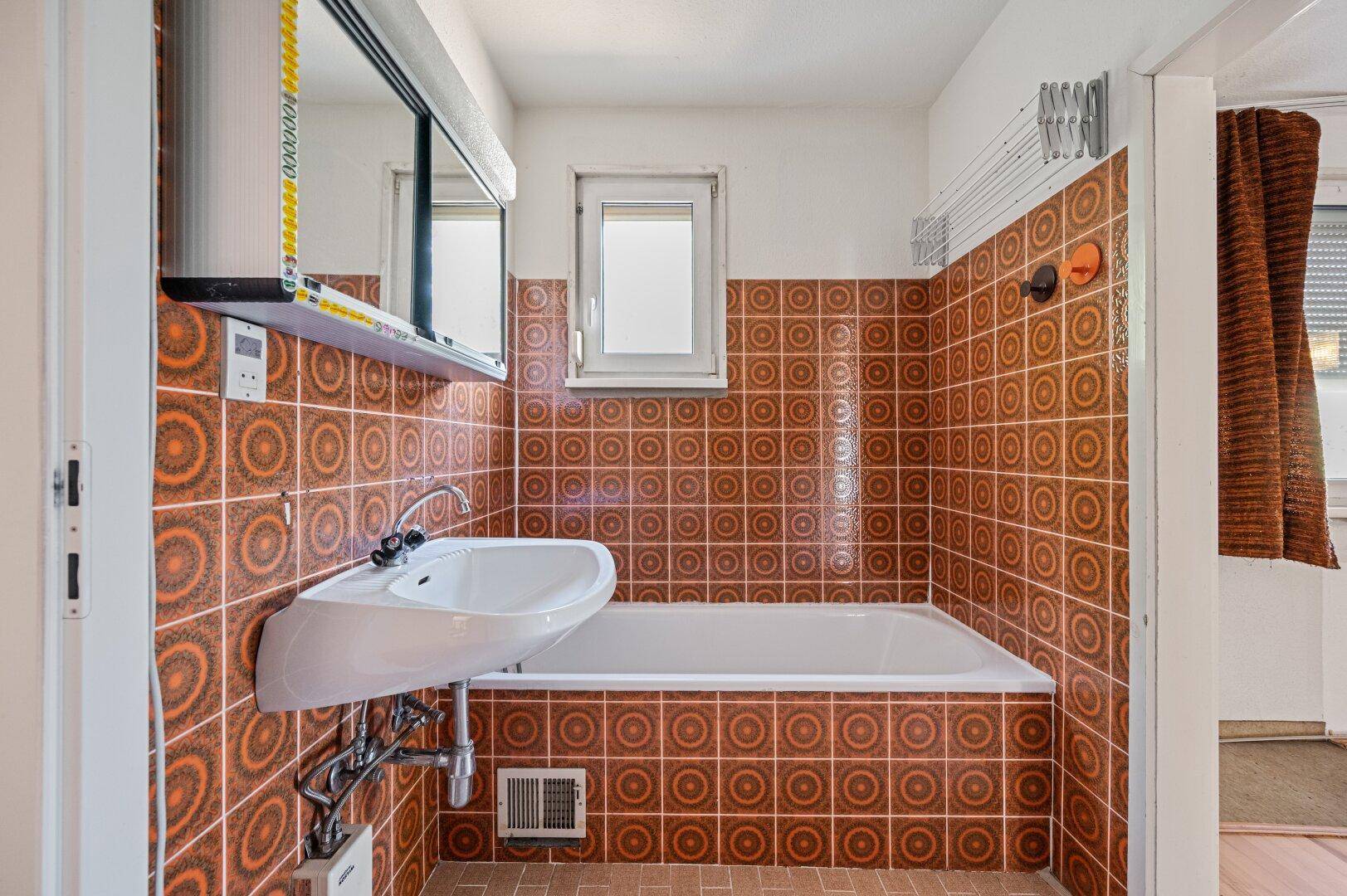 Badezimmer mit Badewanne, Waschbecken und Fenster, charakteristisch für die 80er Jahre.