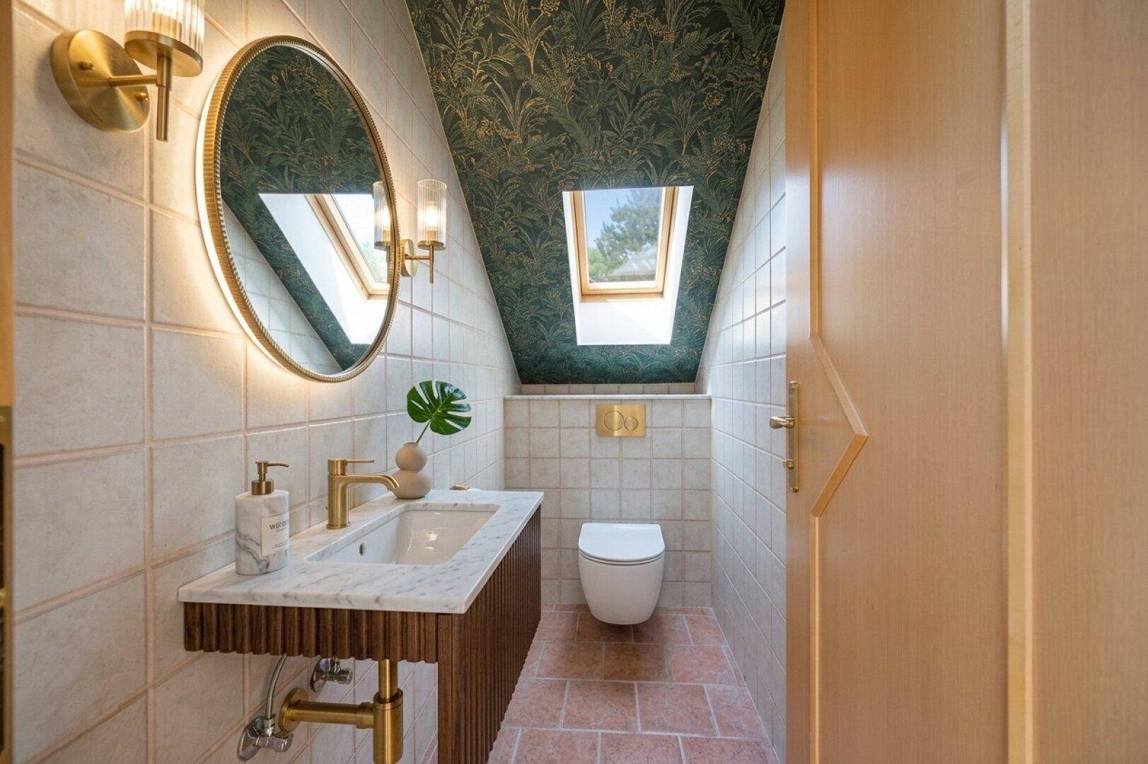 Modernes Gäste-WC mit gemusterter Tapete, Dachfenster und eleganten goldenen Armaturen.