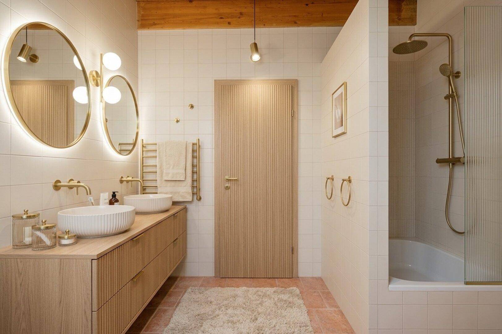 Modernes Badezimmer mit Doppelwaschbecken, Dusche, Handtuchheizkörper und goldenen Armaturen.