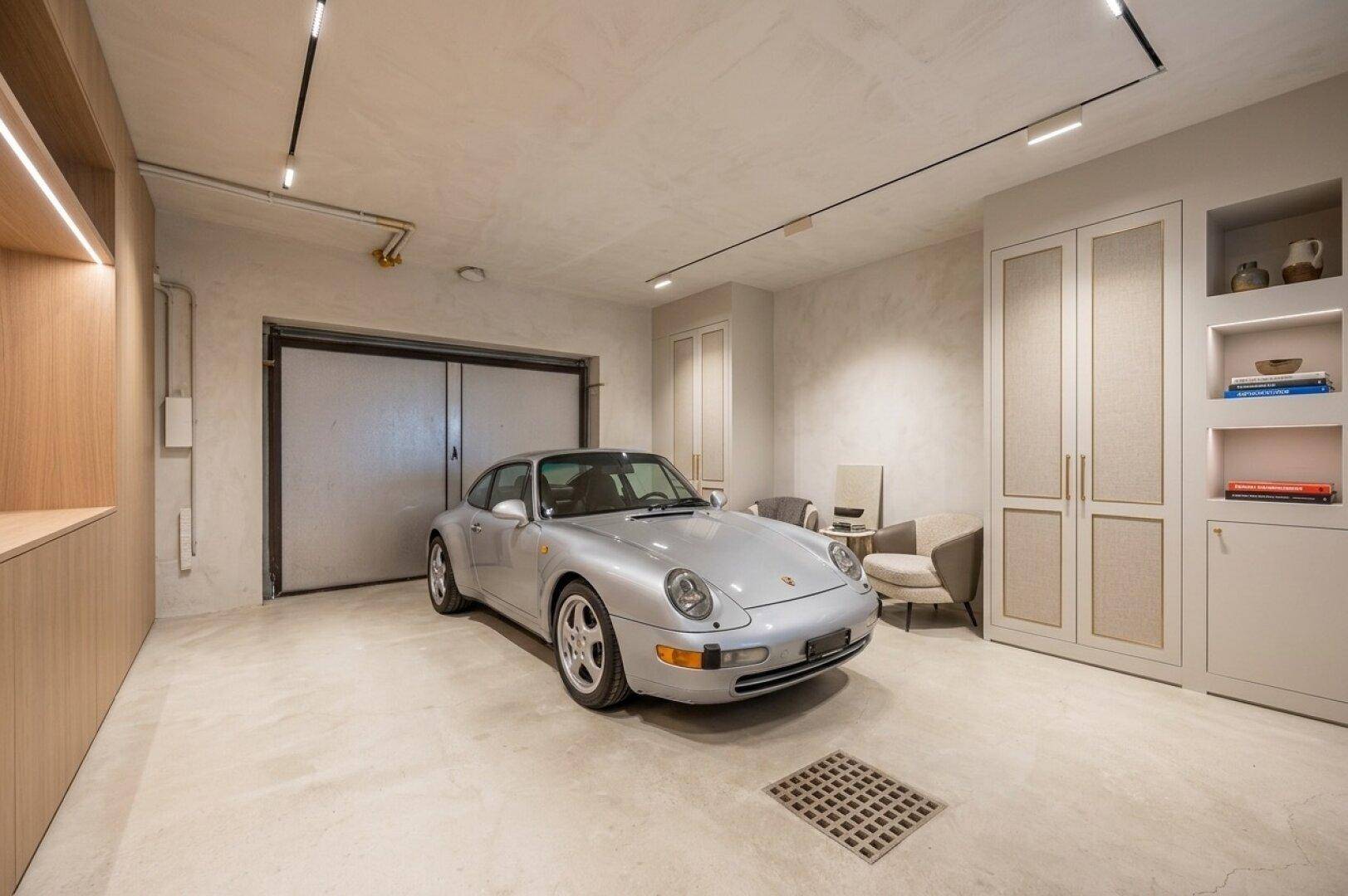 Moderne Garage mit poliertem Betonboden, integrierten Schränken und einem Sportwagen.