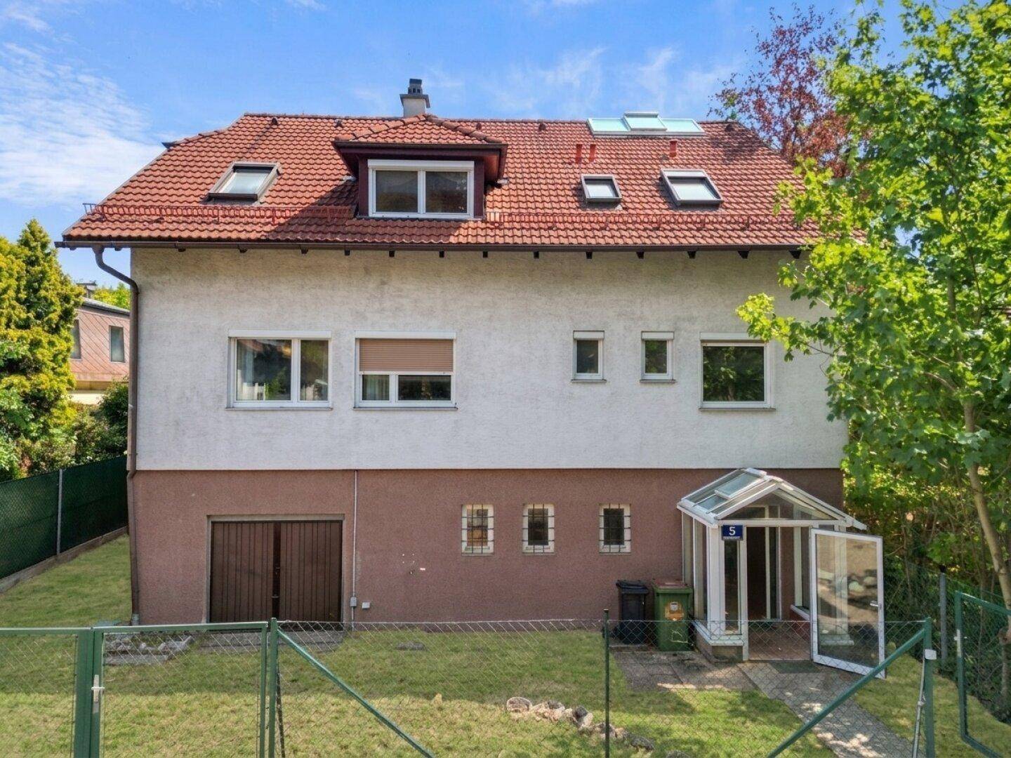 Vorderansicht eines Hauses mit Satteldach, Garage und Gartenbereich vor der Renovierung.