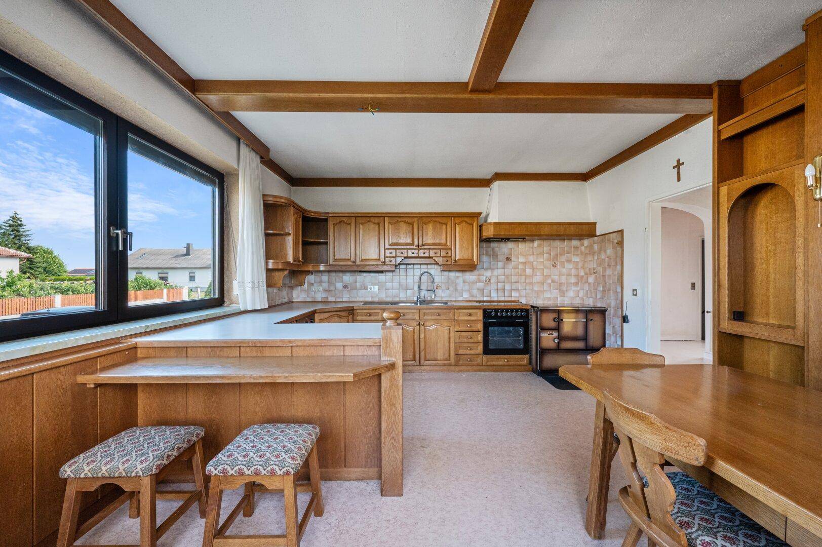 Geräumige Küche mit traditionellen Holzschränken, Holzbalken und einem integrierten Essbereich.