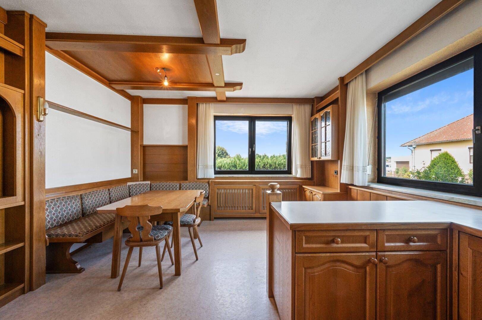 Gemütlicher Essbereich in der Küche mit eingebauter Holzbank und traditionellen Holzmöbeln.