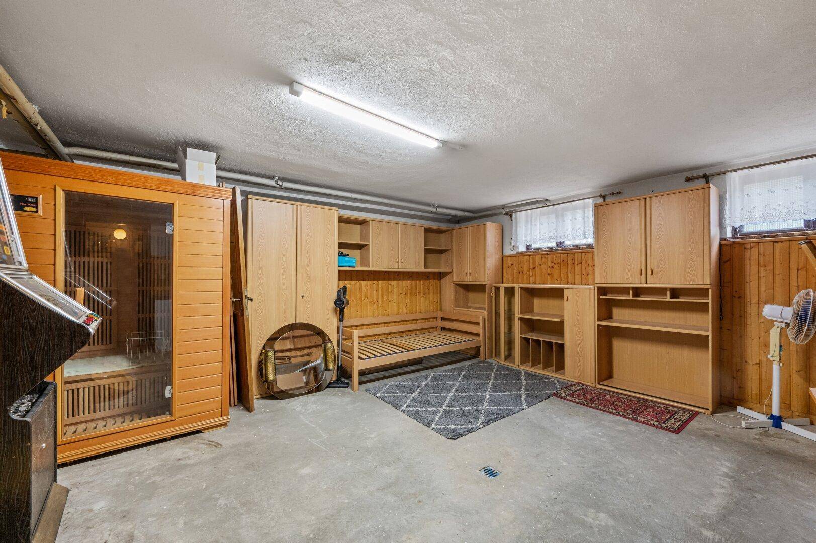 Geräumiger Kellerraum mit eingebauter Sauna, Holzschränken und Betonboden.