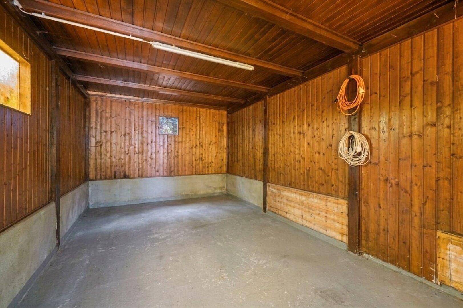 Geräumige Garage mit Holzverkleidung an Wänden und Decke sowie Betonboden.