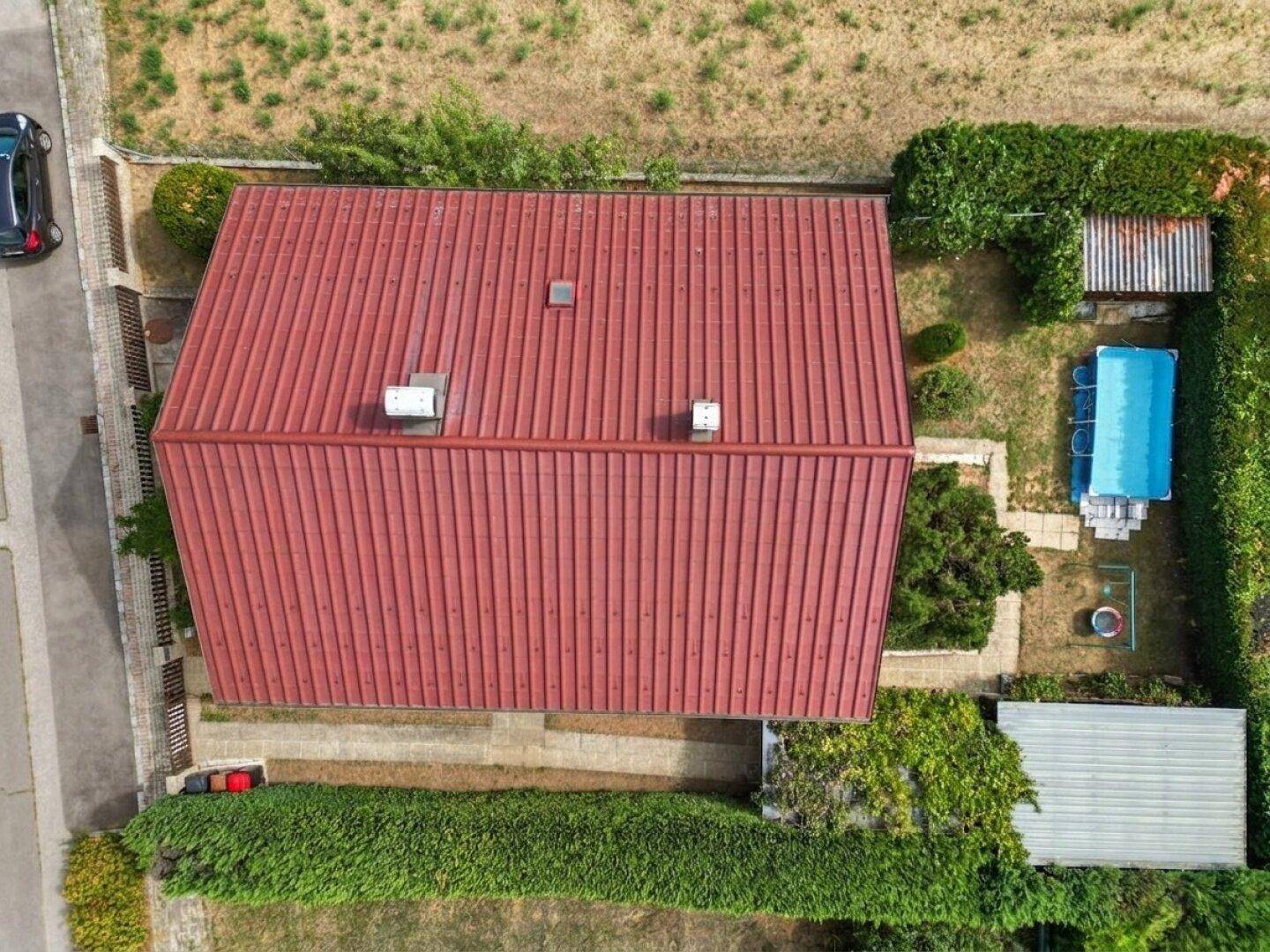 Luftaufnahme des Hauses mit rotem Satteldach, Garten und Aufstellpool.