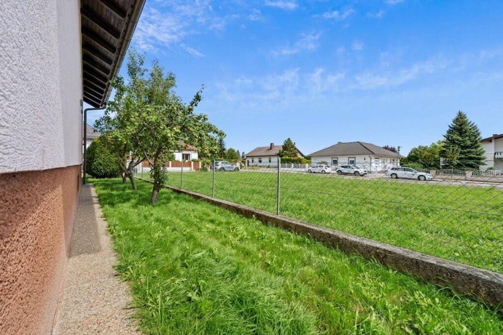 Weitläufige Rasenfläche neben dem Haus mit Blick auf die ländliche Umgebung.