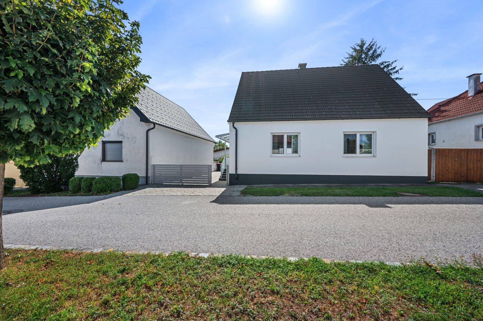 Ansicht des Einfamilienhauses von der Straße mit gepflegtem Vorgarten und Zufahrt.