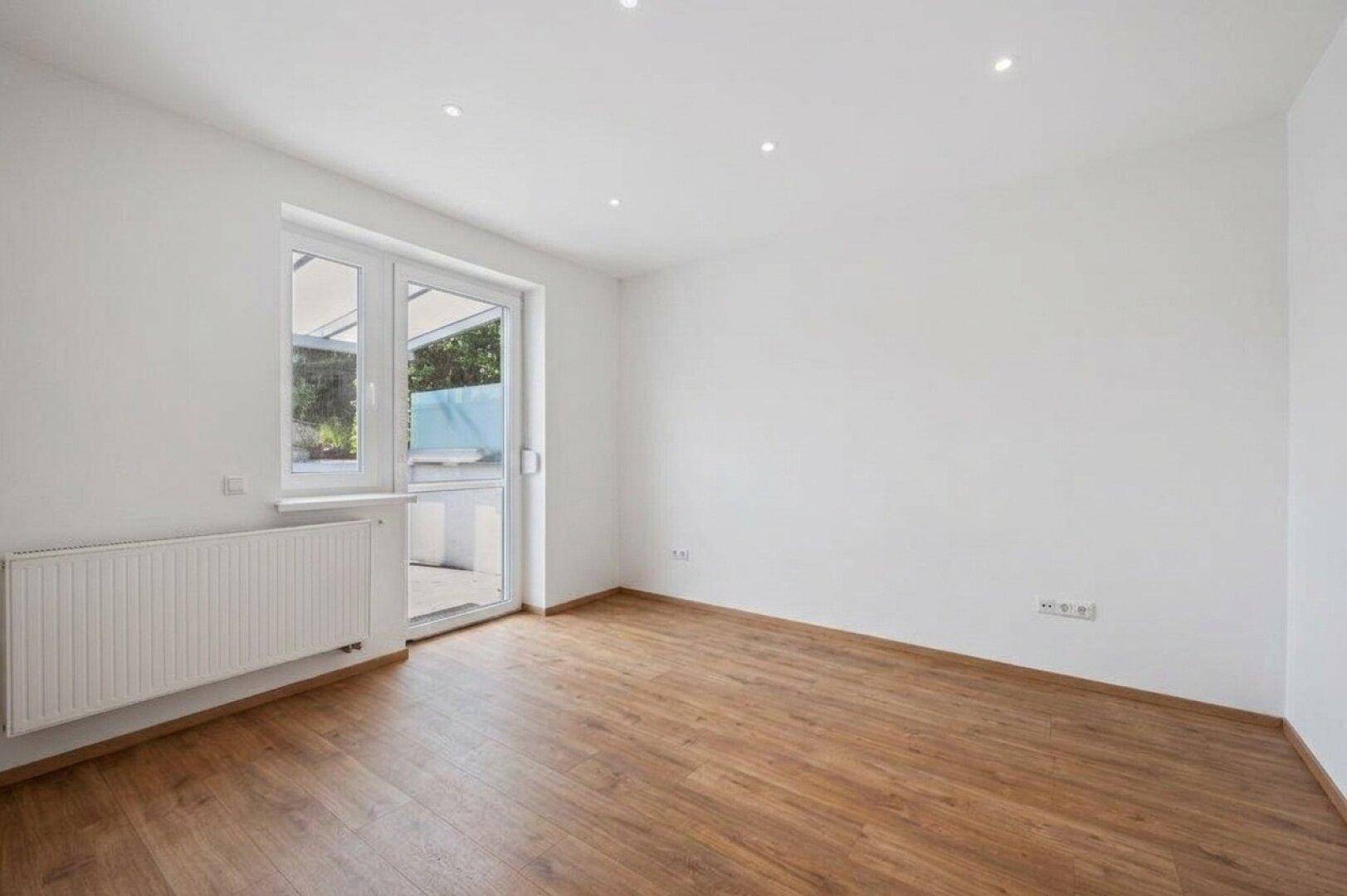 Geräumiges Zimmer mit Laminatboden und Terrassenzugang, bietet viel Licht und frische Luft.