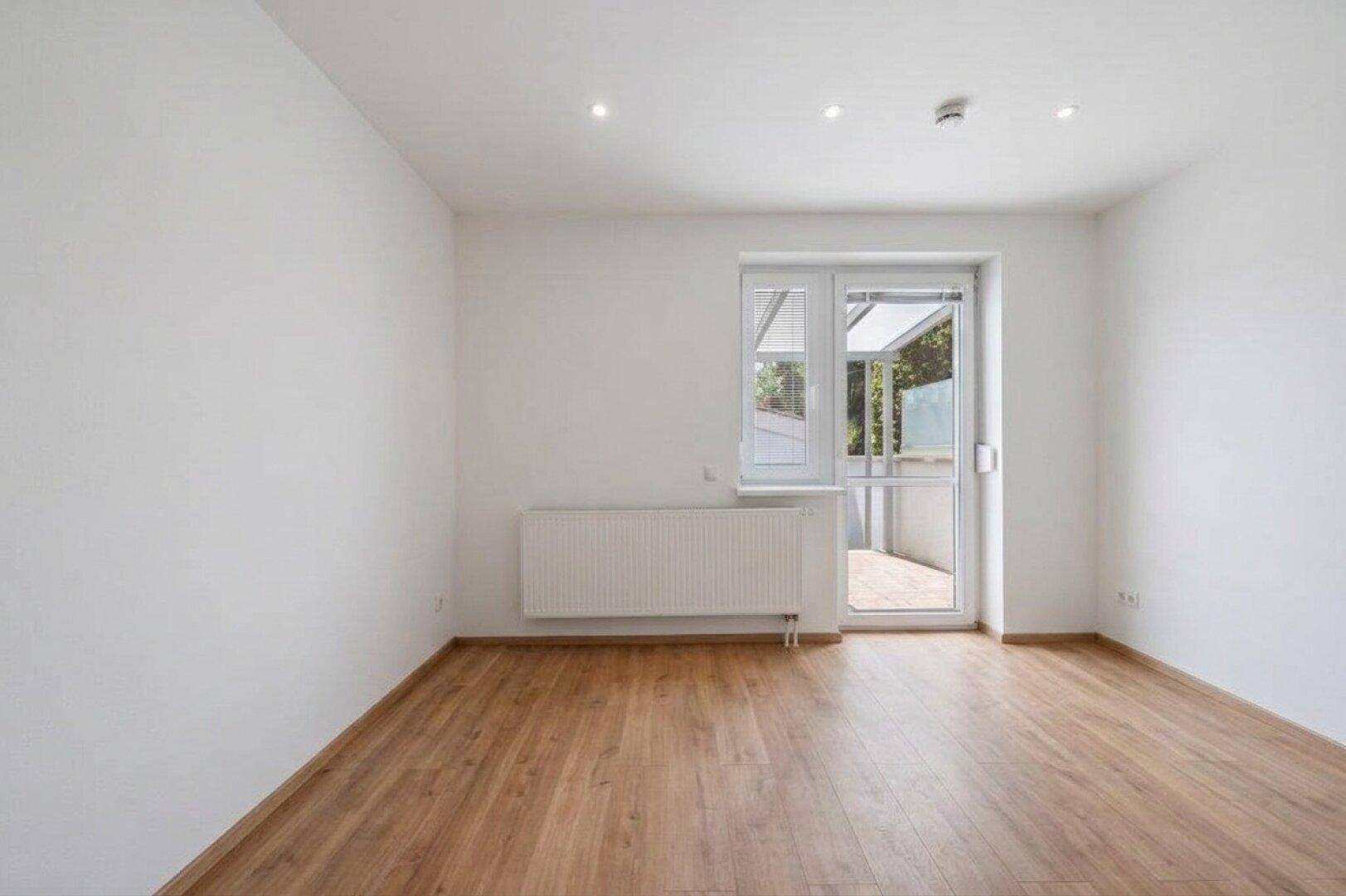 Helles Zimmer mit Laminatboden und direktem Zugang zur Terrasse, ideal als Schlaf- oder Wohnzimmer.