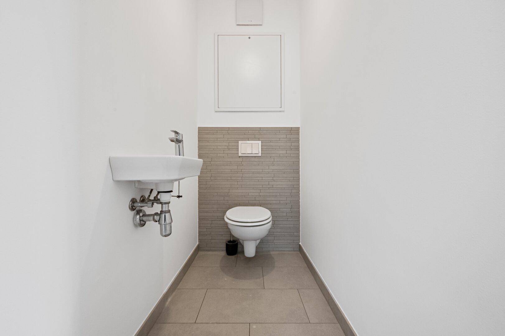 Kleines Gäste-WC mit wandhängendem WC und Handwaschbecken.