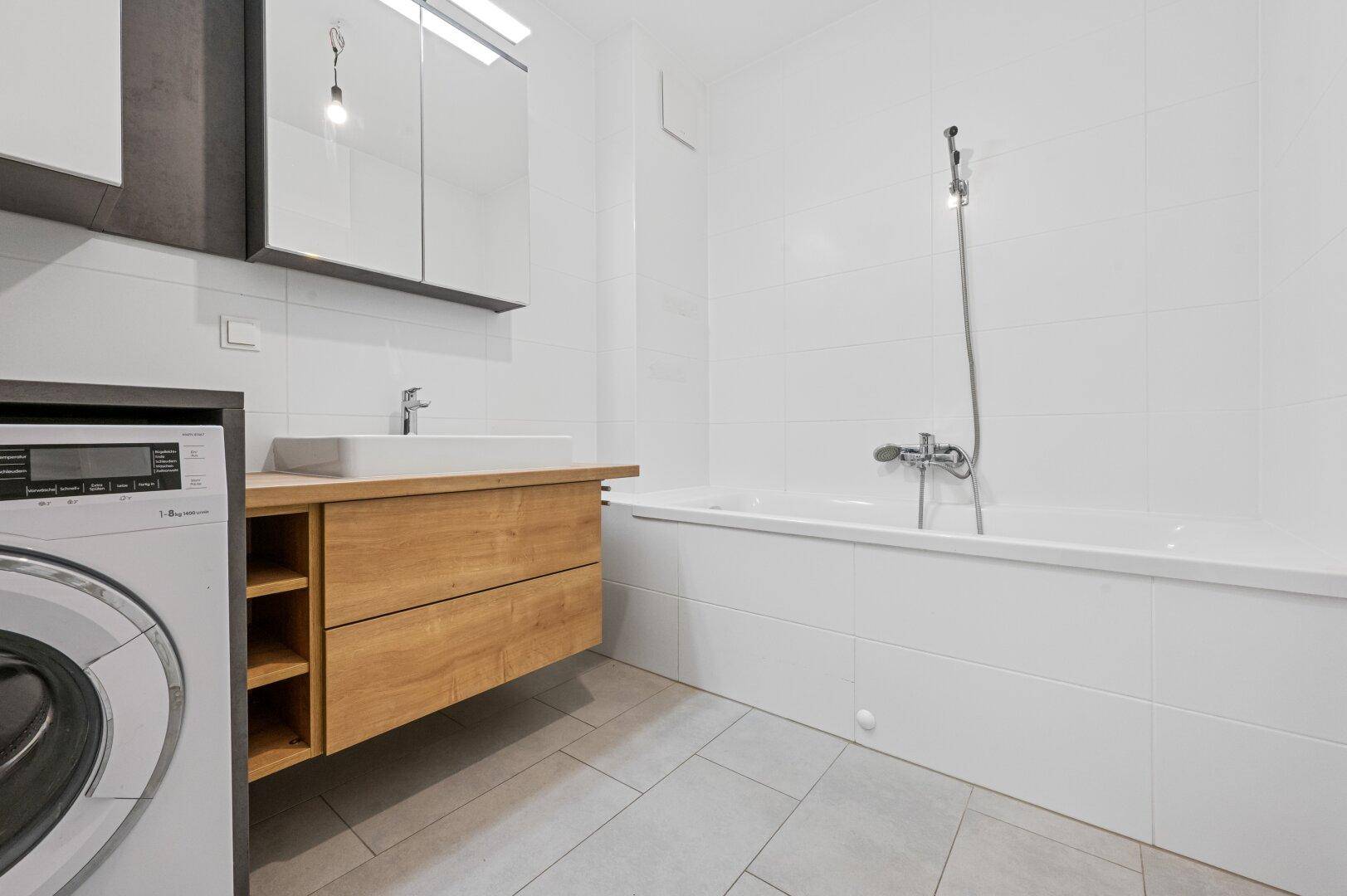 Helles Badezimmer mit Badewanne, modernem Waschtisch und Fliesenboden.