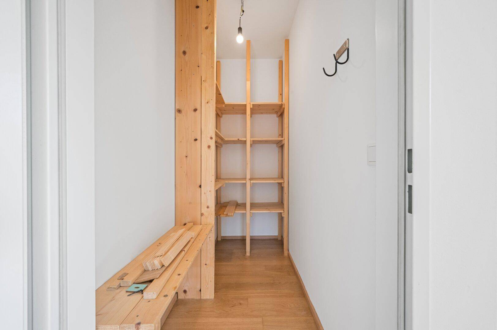 Praktischer Abstellraum mit Holzregalen, ideal für zusätzlichen Stauraum.