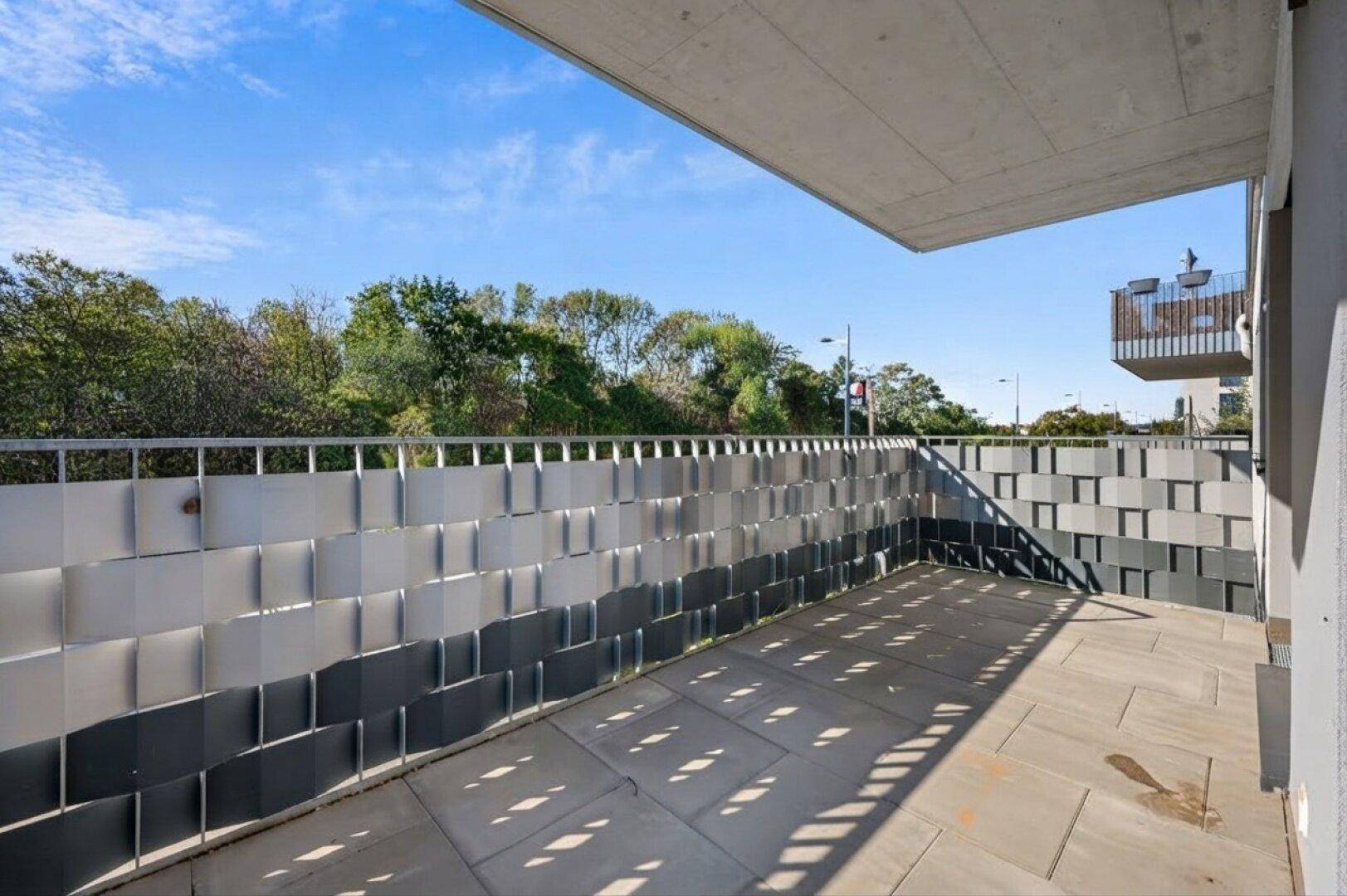 Geräumiger Balkon mit modernen Sichtschutzelementen und Blick ins Grüne.
