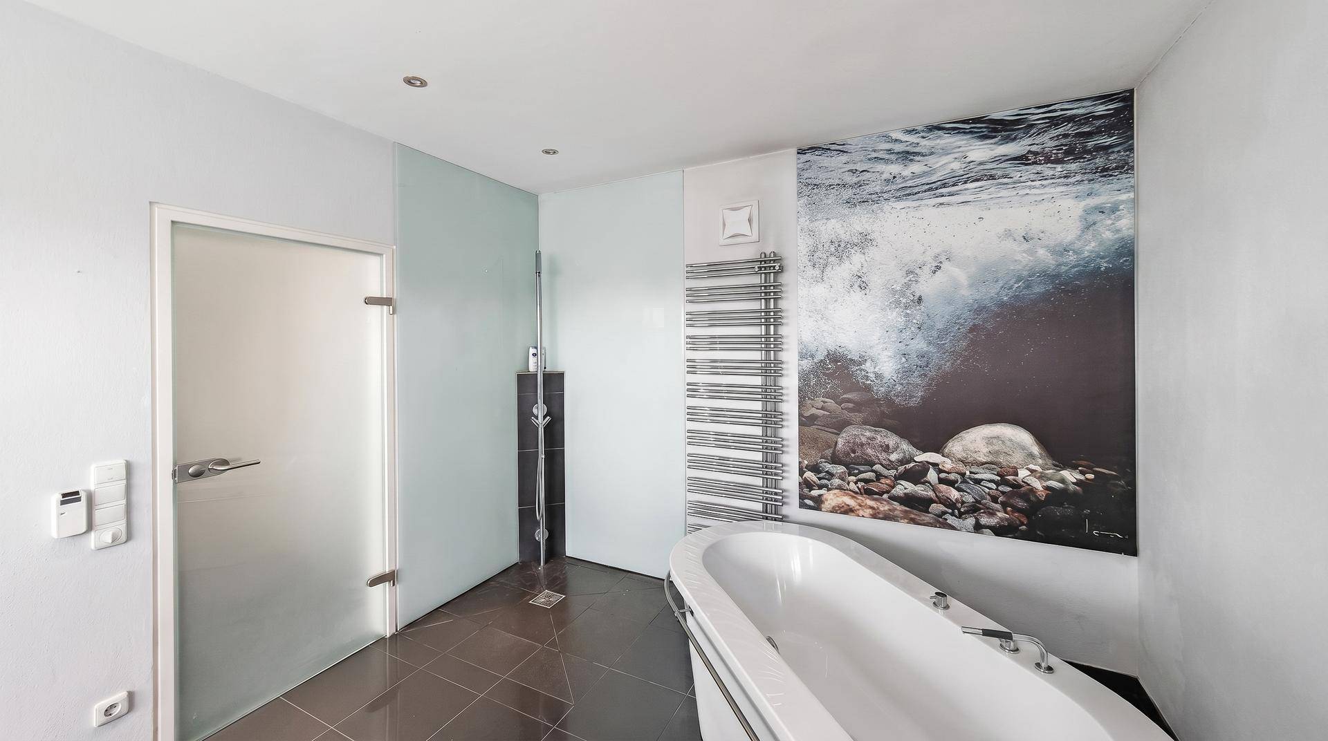 Modernes Badezimmer mit freistehender Badewanne, begehbarer Dusche und beheiztem Handtuchhalter.