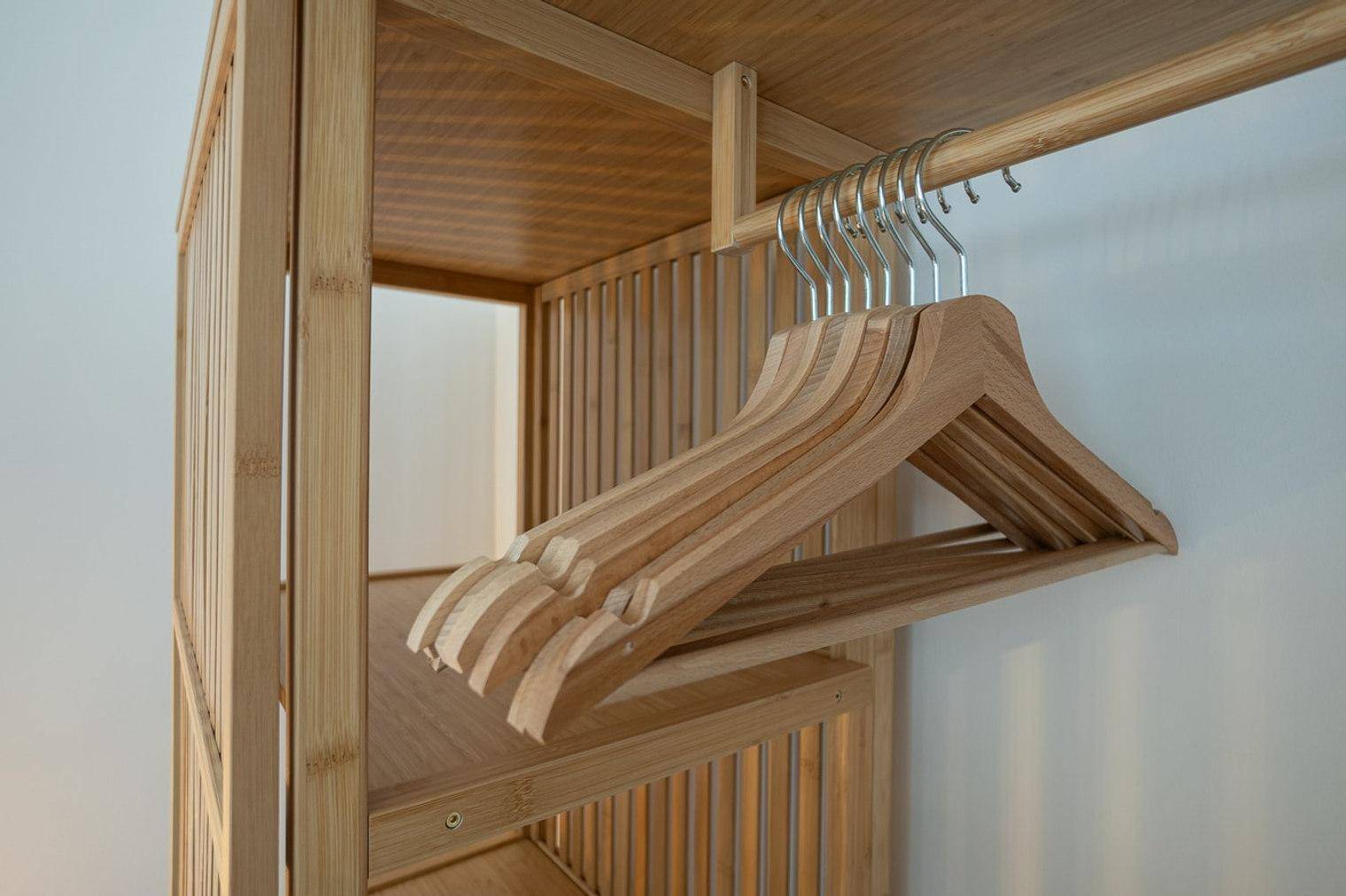 Detailansicht einer offenen Holzgarderobe mit Kleiderbügeln, die Funktionalität bietet.