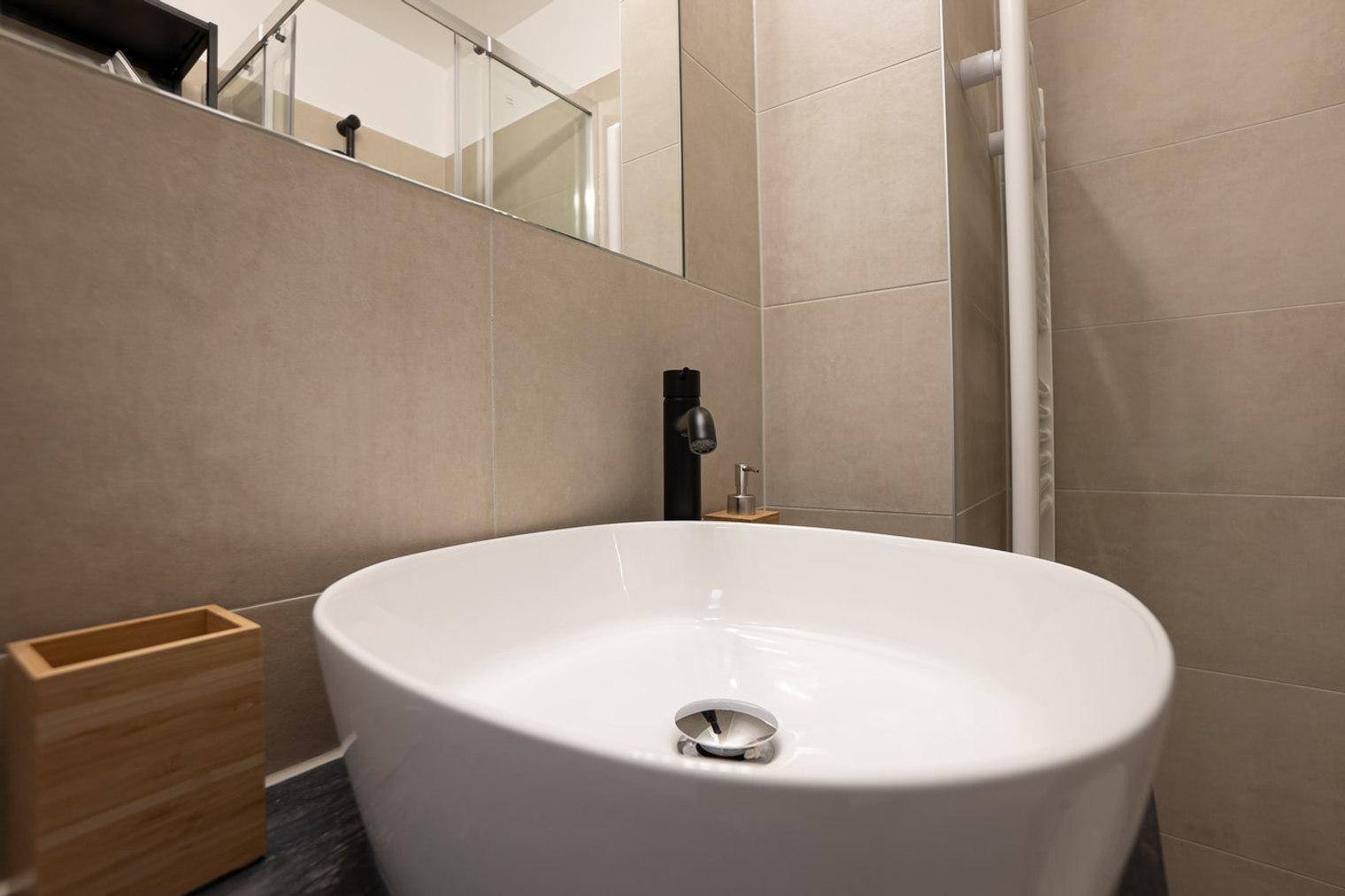 Detailansicht des modernen Waschbeckens mit schwarzem Wasserhahn im Badezimmer.