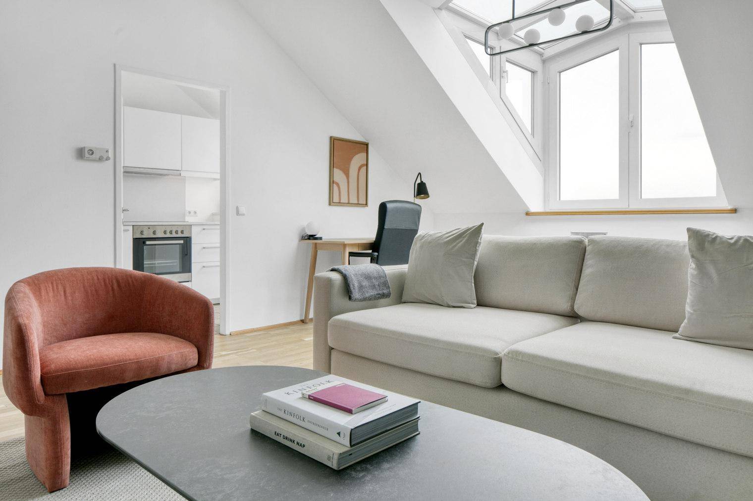 Wohnbereich mit Sofa und Blick auf die angrenzende Küchenzeile im Dachgeschoss.