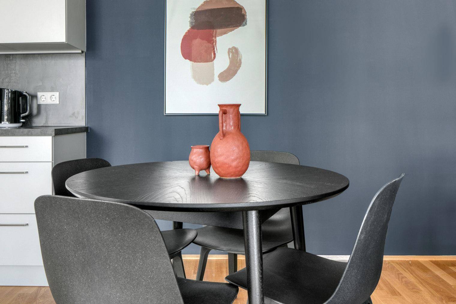 Essbereich mit schwarzem Holztisch und Stühlen, ergänzt durch moderne Wandkunst.