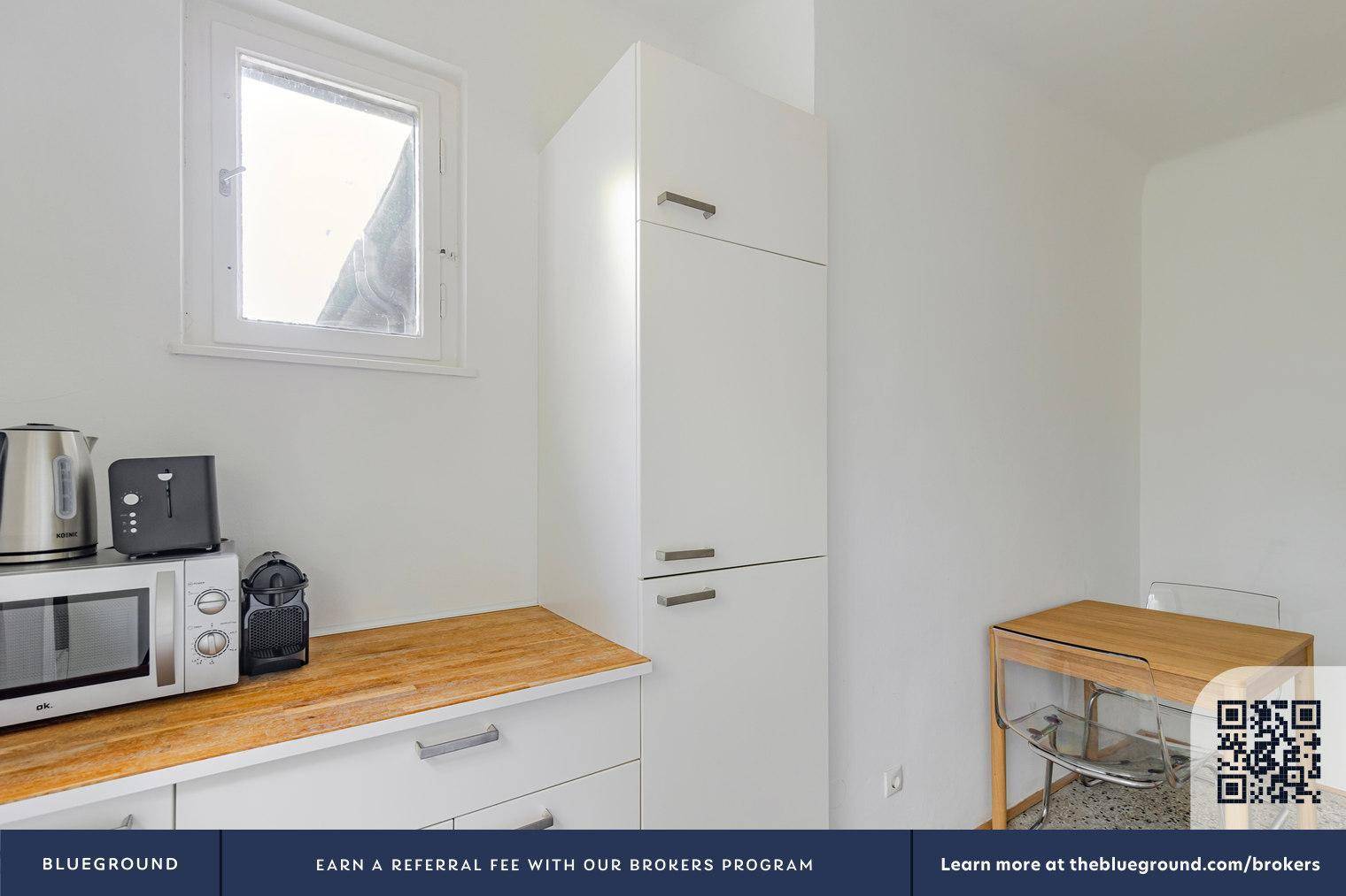 Küchenzeile mit Mikrowelle, Wasserkocher und Kaffeemaschine auf einer Holz-Arbeitsplatte.