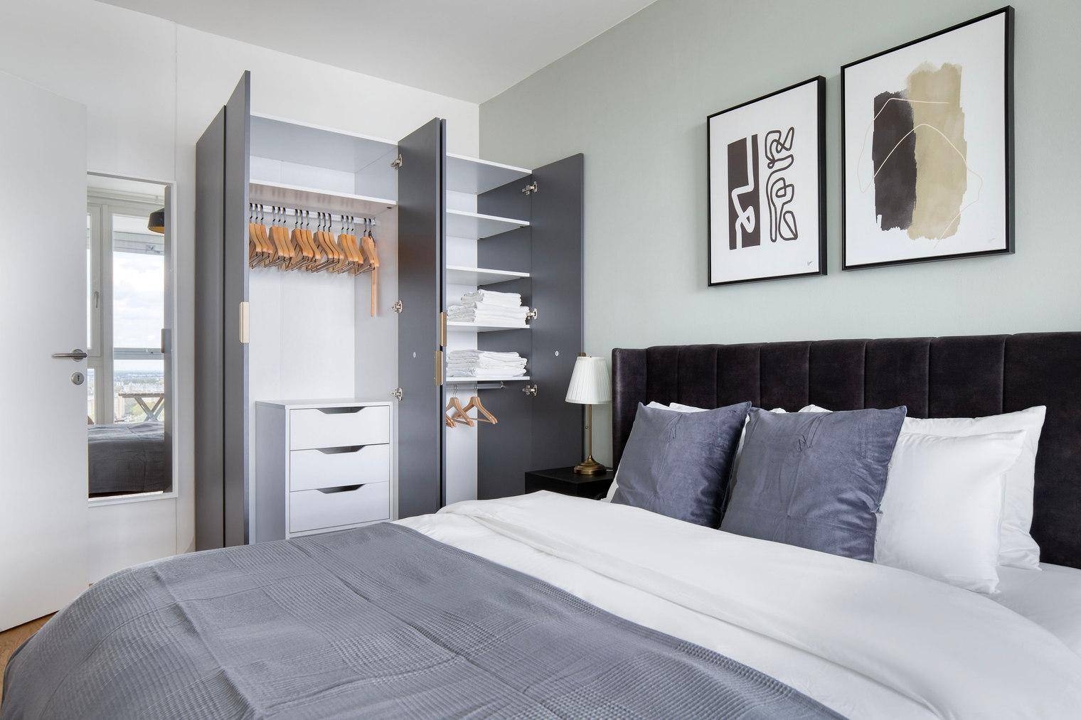 Schlafzimmer mit offenem Kleiderschrank, der Kleiderbügel und Ablageflächen bietet.