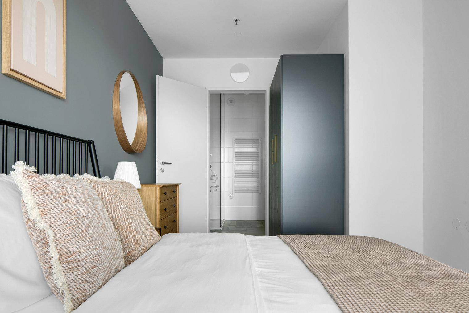 Schlafzimmer mit Zugang zum Badezimmer und einem modernen Kleiderschrank.