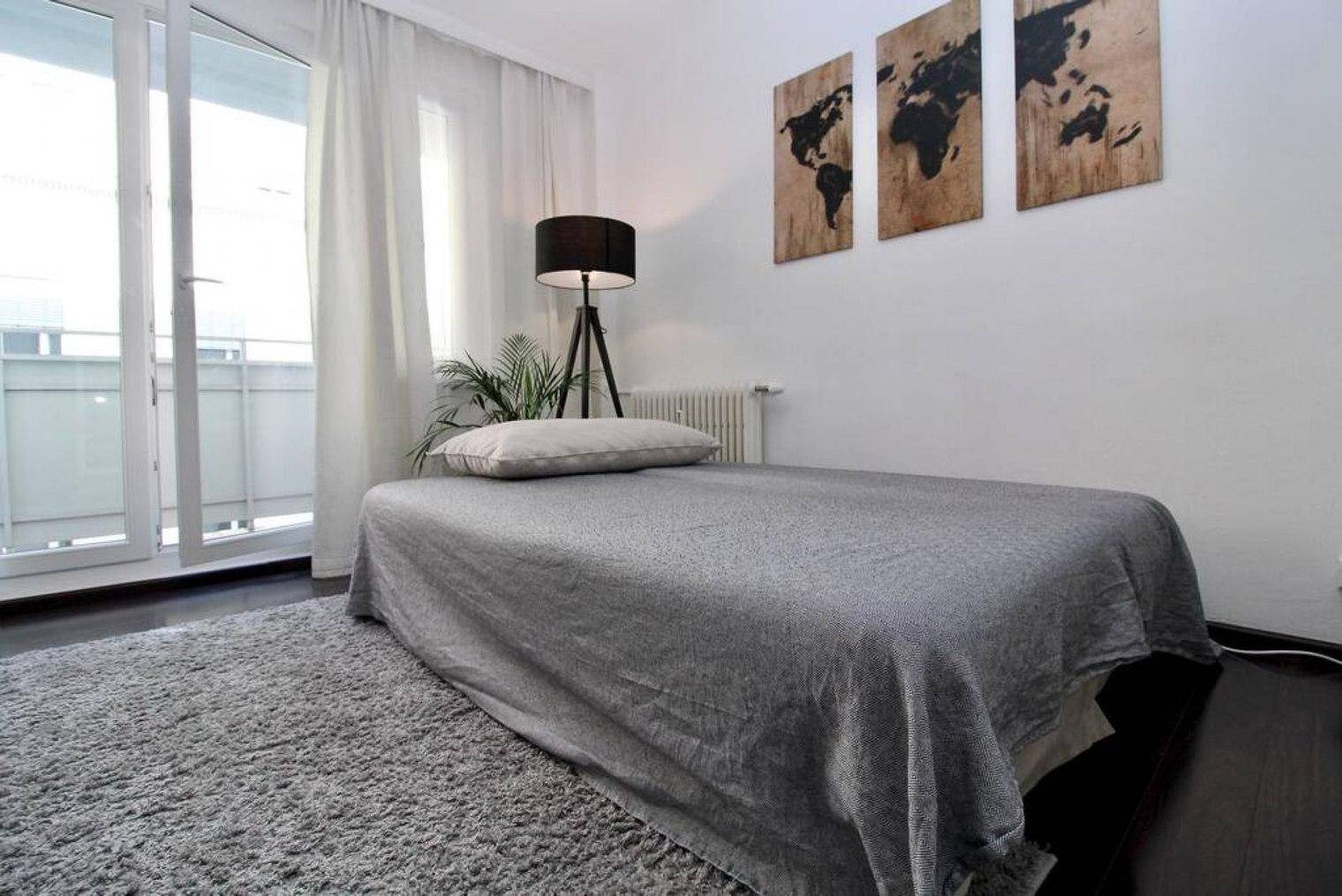 Einzelbett oder Sofa im Wohnbereich mit Zugang zu einem hellen Balkon.