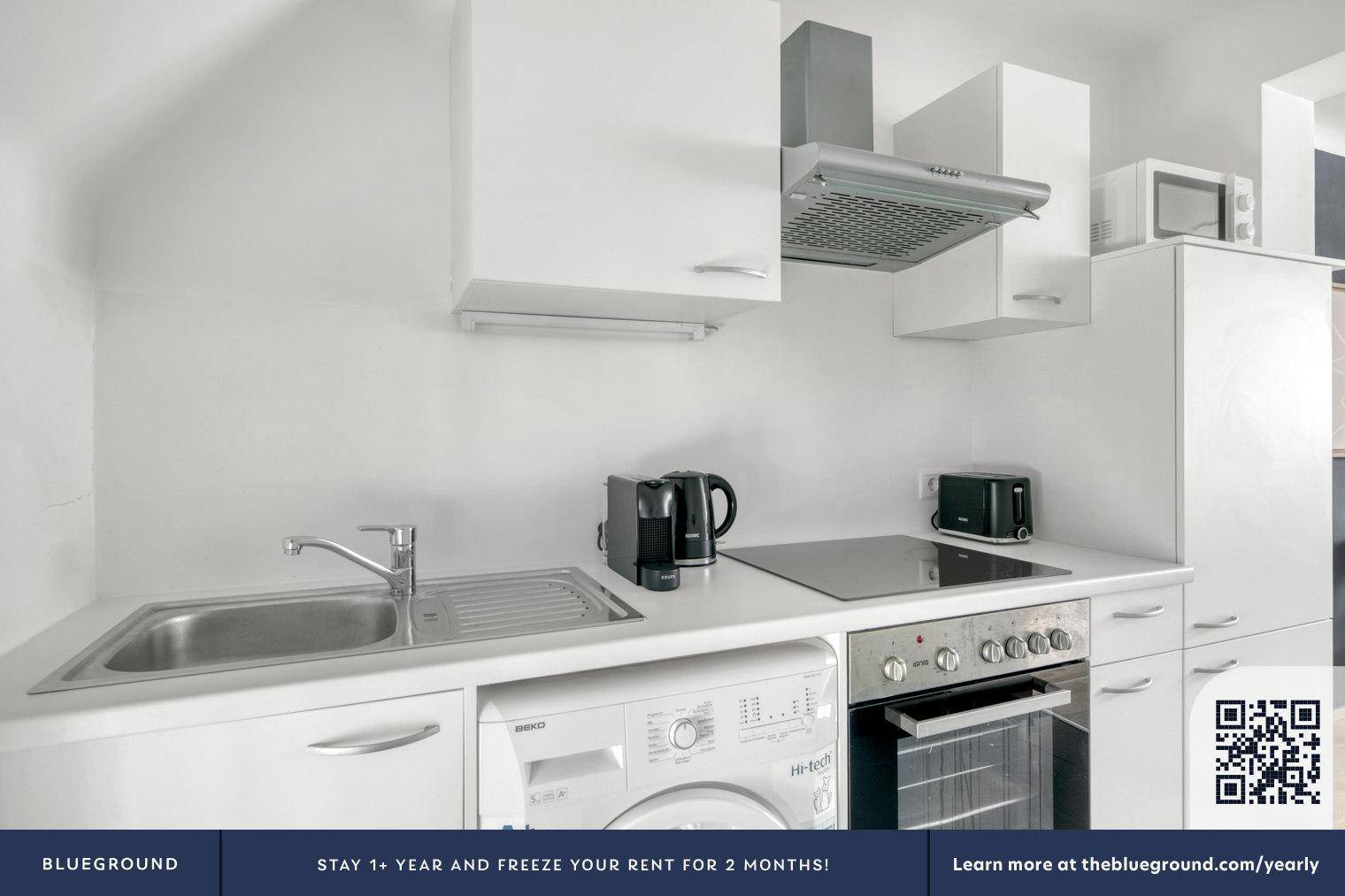 Kompakte, moderne Küche mit weißen Schränken, Spüle und integrierter Waschmaschine.