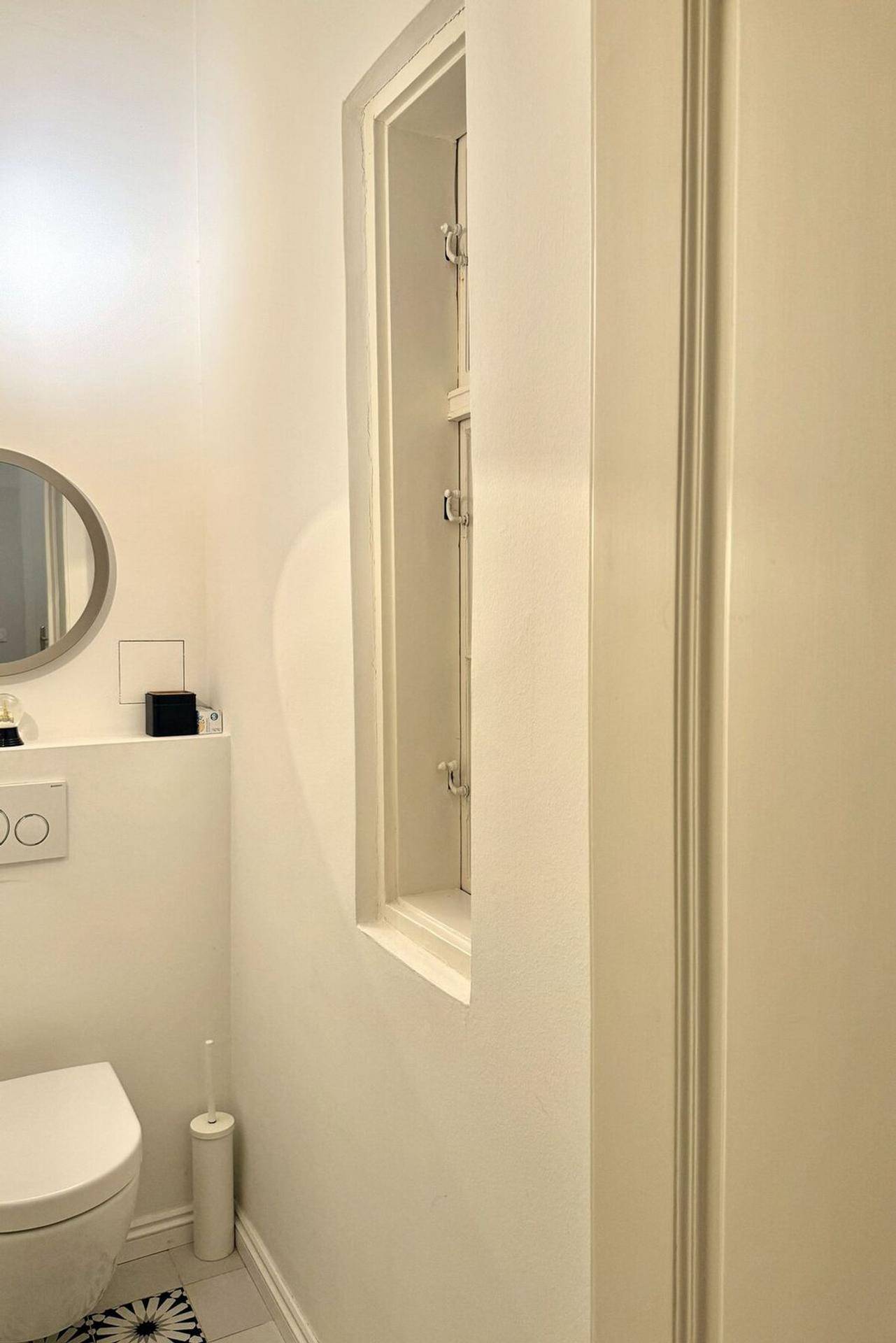 Helles Gäste-WC mit wandmontierter Toilette und kleinem Fenster.
